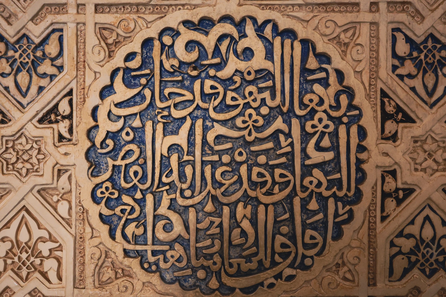 Intricate arabic calligraphy carved into a textured wall