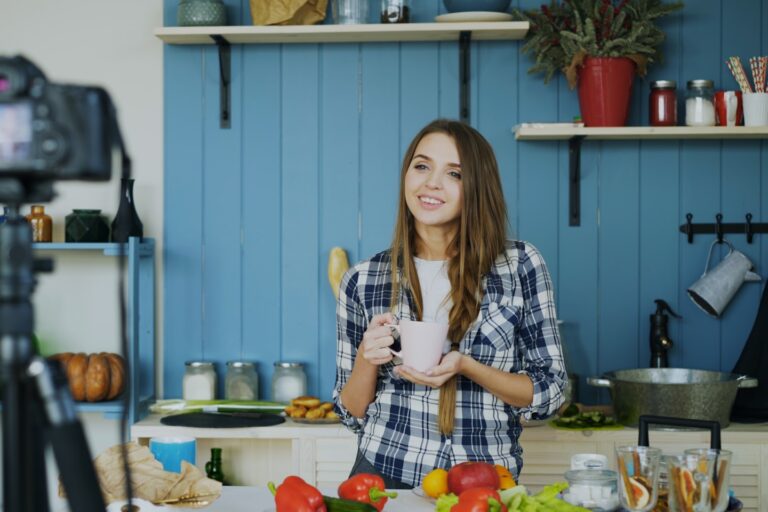 Young attractive woman recording video food blog about cooking on dslr camera in kitchen at home